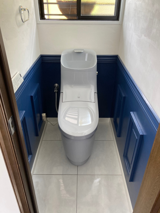 施工後の1階のトイレのお写真です。<br />
お客様自身で貼り替えられた壁紙と青いトイレがよく合っています。